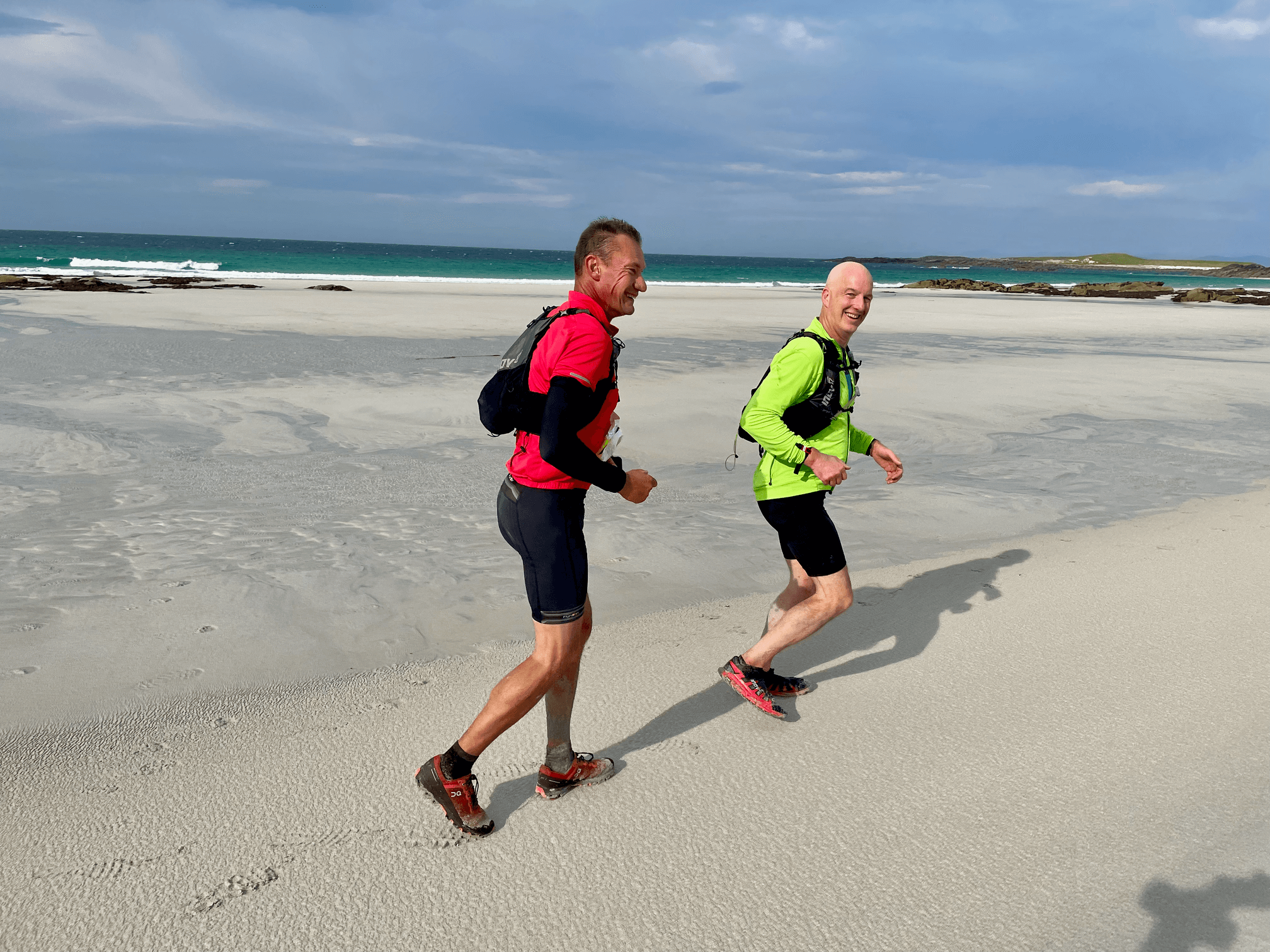 Two men running along a beach.