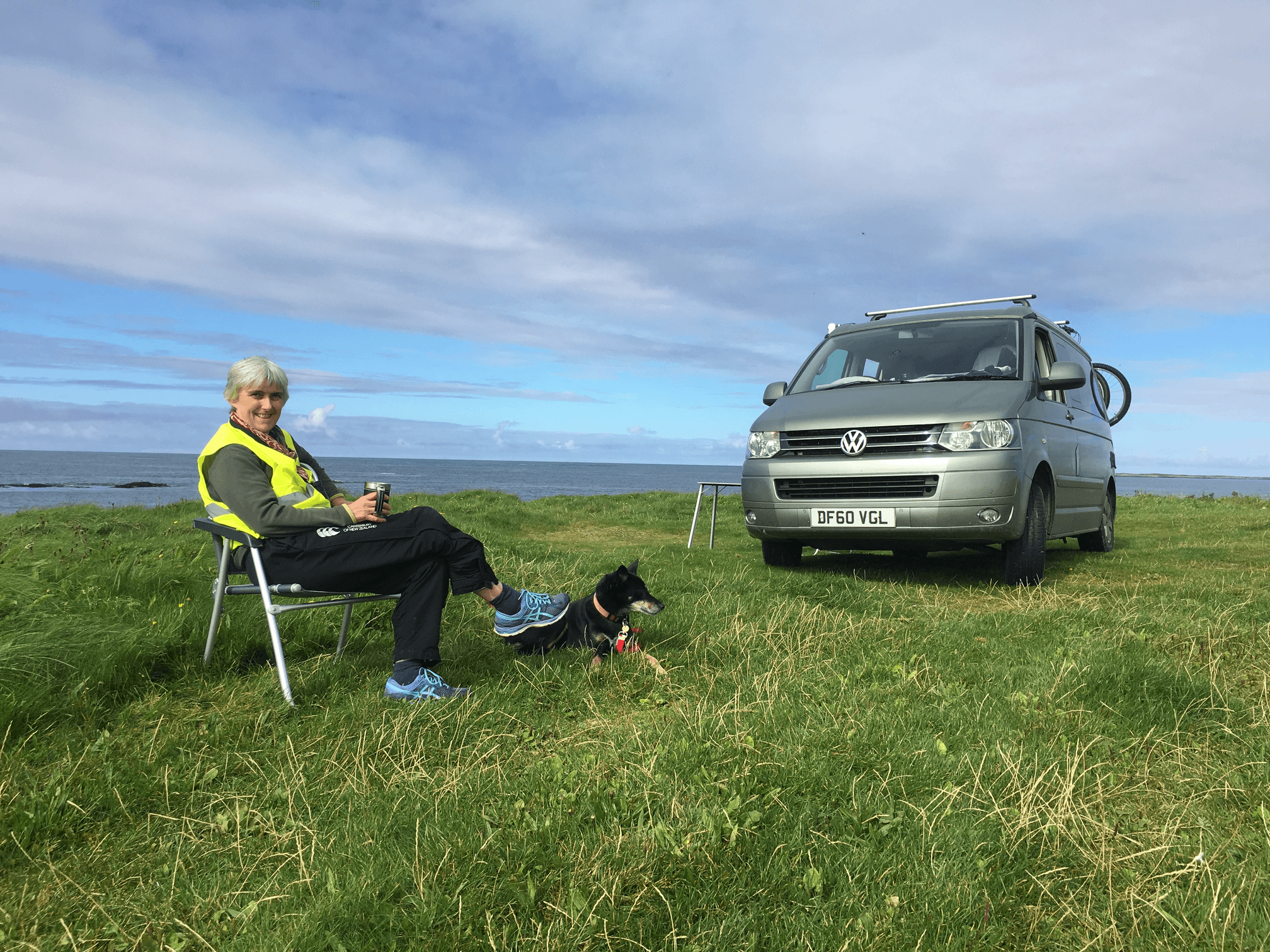 A woman sits in a high-vis yellow vest with a dog.