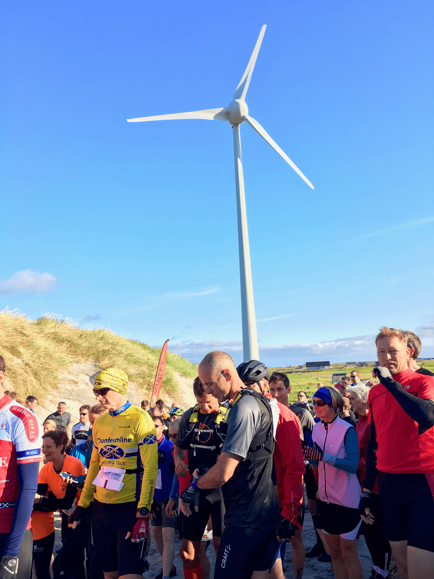 A group of people in running gear assembled beneath a wind turbine.