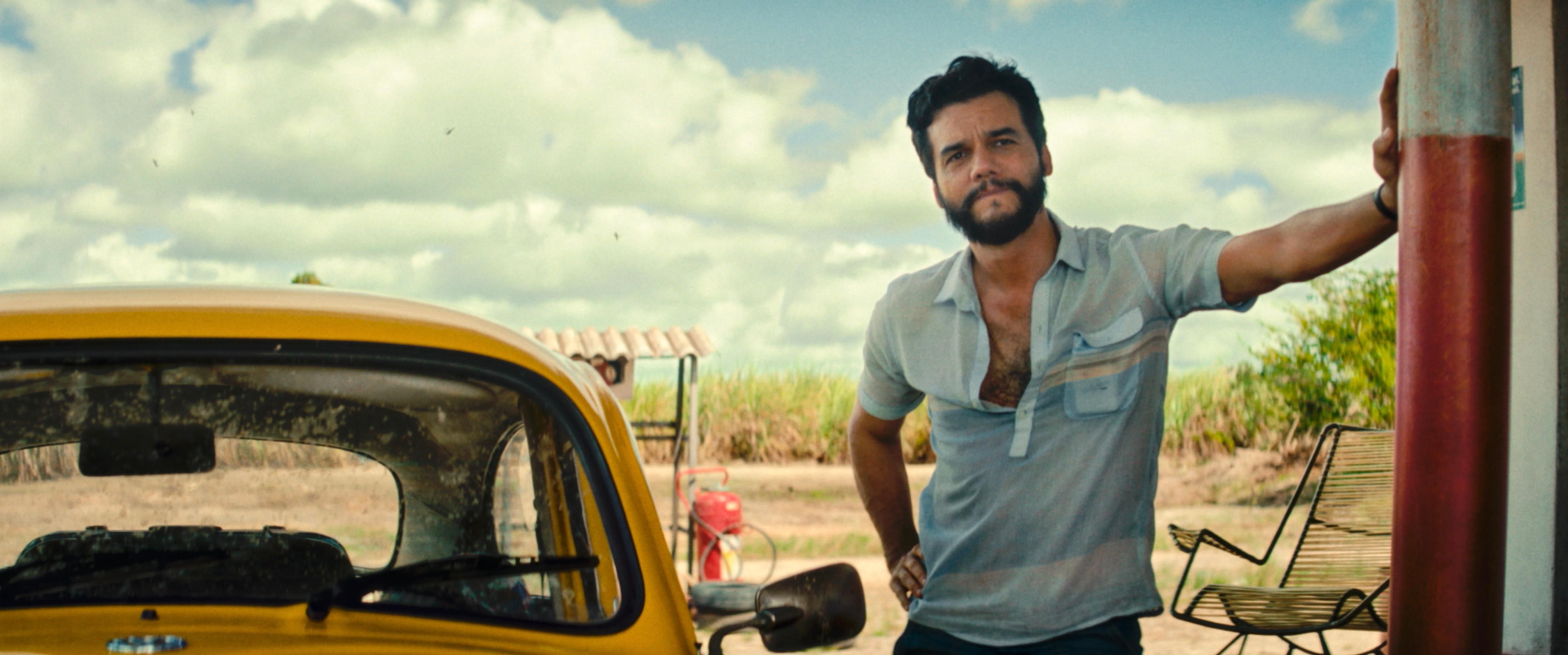 A man standing beside a yellow VW Beetle